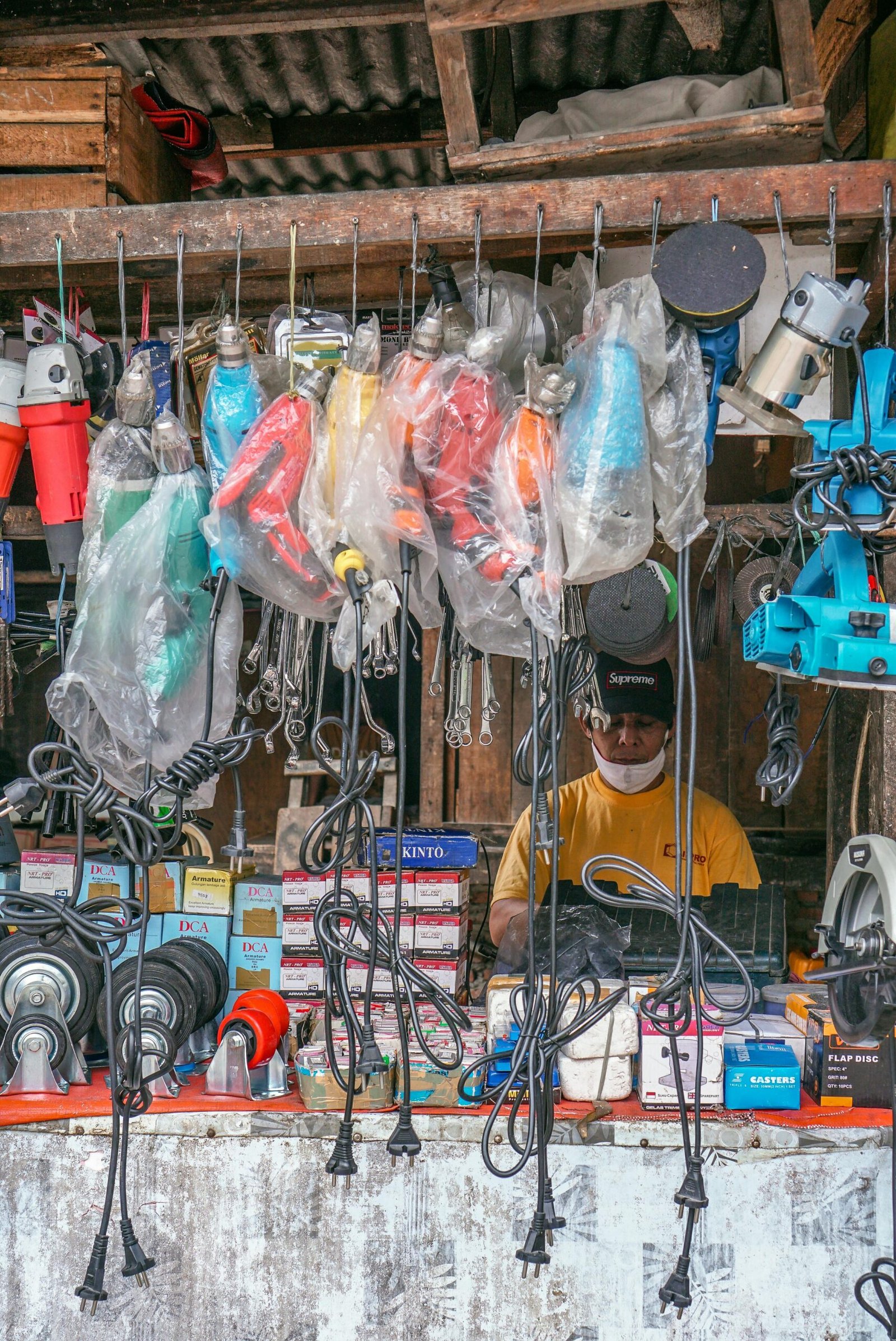 Vibrant electric tools hanging in a market stall, showcasing a variety of power tools for sale.